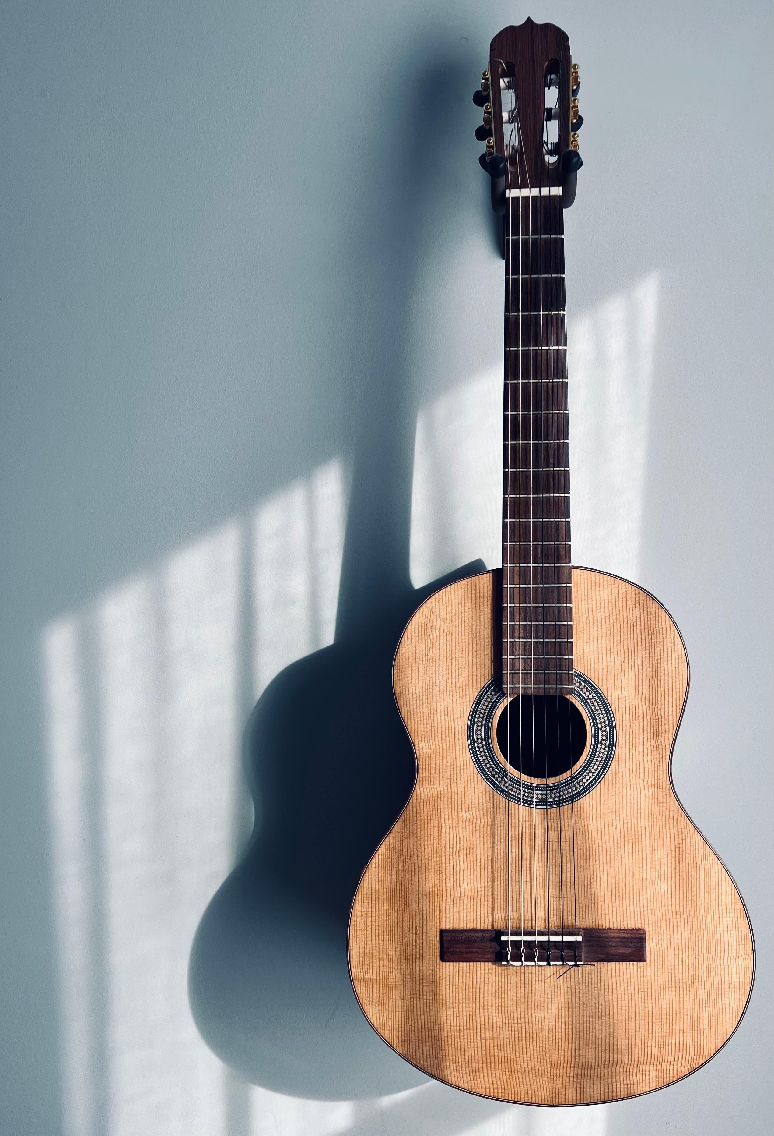 A finished SugarTree guitar at rest on the workshop wall.
